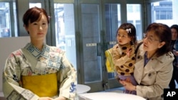 Customers watch android robot "Aiko Chihira" at the reception of Mitsukoshi department store in Tokyo, Monday, April 20, 2015. The lifelike android robot, which was developed by Japanese electronics manufacturer Toshiba, marked her first day at work as a 