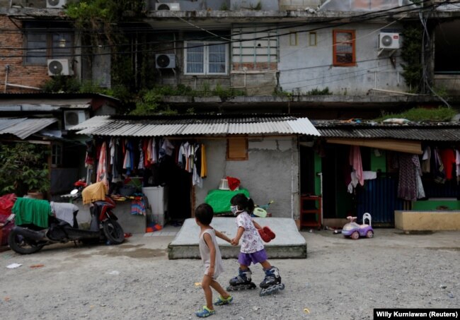 Anak-anak memakai masker bermain di sepanjang jalan di kawasan pemukiman padat penduduk, di tengah penyebaran COVID-19, di Jakarta, 4 April 2020. (Foto: REUTERS/Willy Kurniawan)