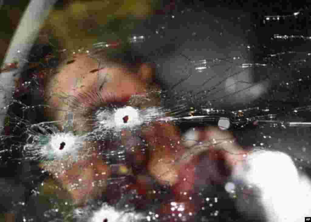 The dead body of a gunman is seen inside a car behind a bullet-riddled windshield in Jungapeo in the state of Michoacan January 19, 2012. In a shootout between gunmen and soldiers, two gunmen were killed while other three managed to escape, according to l