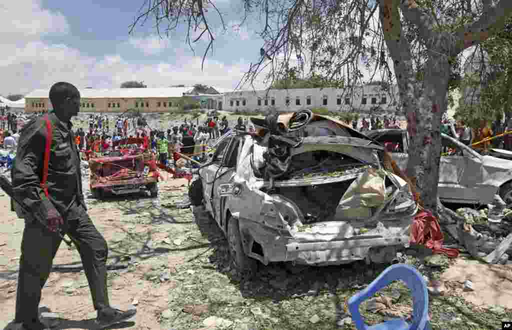 A Somali soldier walks near the wreckage of vehicles at the scene of a blast outside the compound of a district headquarters in the capital Mogadishu.