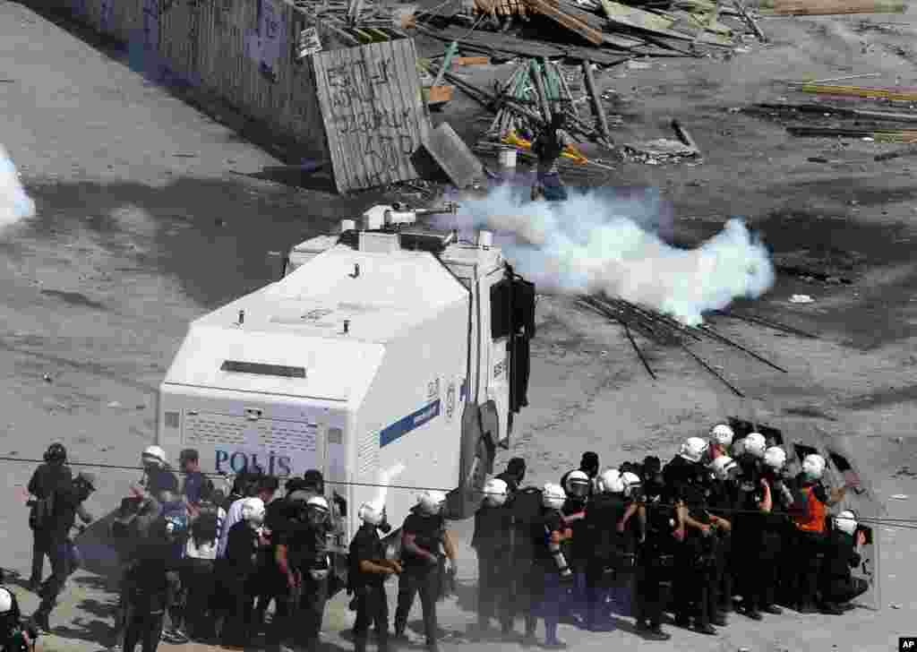 A protester runs to avoid tear gas as police take cover next to a water cannon in Taksim Square in Istanbul, June 11, 2013.