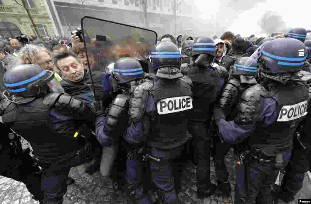 Employees of PSA Peugeot Citroen face French riot policemen during a demonstration in front of the Peugeot headquarters in Paris to protest the closure of the PSA Aulnay automobile plant, the government&#39;s economic policy, and industrial layoffs.