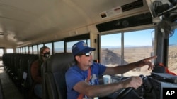 School bus driver by Kelly Maestas travels along a dirt road, with social worker Victoria Dominguez, outside Cuba, N.M., Oct. 19, 2020.