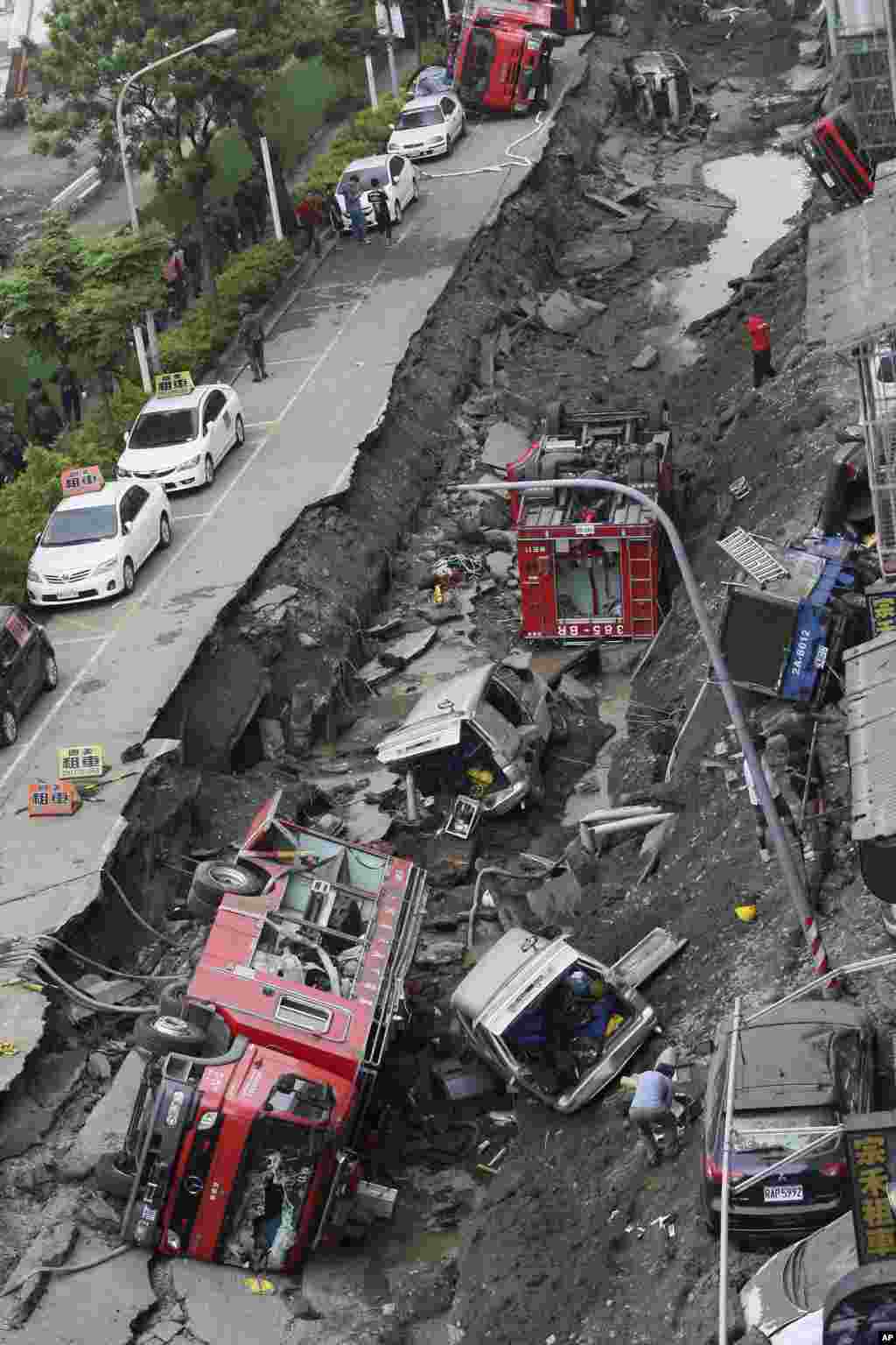 Vehicles are left lie in a destroyed street following multiple explosions from an underground gas leak in Kaohsiung, Taiwan, Aug. 1, 2014. 