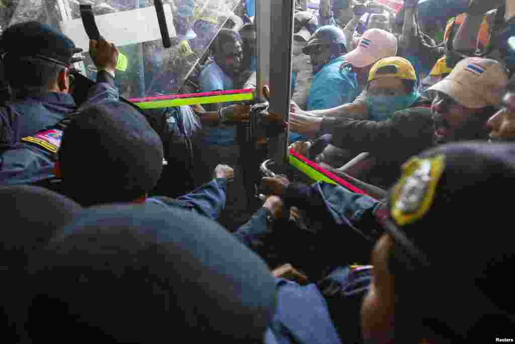 Anti-government protesters battle with riot police at the gate of the gymnasium where candidates register for elections in Bangkok, Dec. 25, 2013.