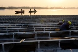 FILE - Chinese employees working, Dec. 11, 2017, on a floating solar power plant in Huainan, a former coal-mining region, in China's eastern Anhui province.