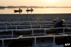 FILE - Chinese employees working, Dec. 11, 2017, on a floating solar power plant in Huainan, a former coal-mining region, in China's eastern Anhui province.
