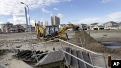 A worker uses a backhoe to clear sand and debris that was carried onshore by surge from superstorm Sandy in Atlantic City, N.J., Oct. 31, 2012.