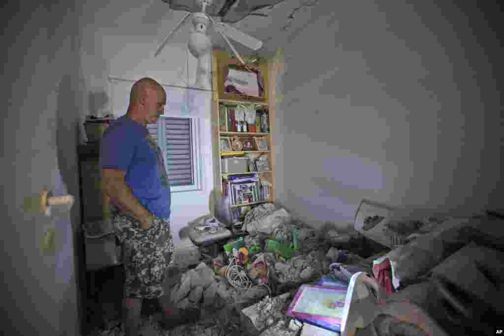 An Israeli looks at damage to his home in a kibbutz near border with the Gaza Strip, July 9, 2014. 