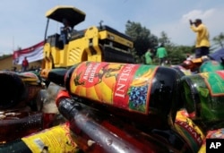 Government officials destroy bottles of illegal alcohol confiscated in Serpong, on the outskirts of Jakarta, Indonesia, April 13, 2018.