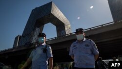 资料照：两名警察在北京街头巡逻，背景是中国中央电视台大楼。（2020年5月19日）