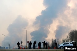 Journalists look on as smoke rises from wildfires south of Fort McMurray, Alberta, Canada, May 6, 2016.