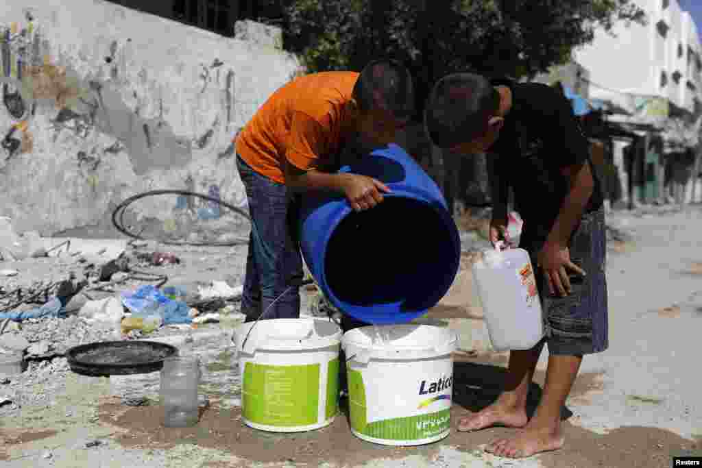 Palestinians youths fetch water from a container after returning to their damaged home in the Beit Hanoun area during a 72-hour ceasefire, Gaza City, Aug. 11, 2014