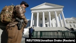Zgrada Senata države Virdžinija, koja je usvojila oštrije propise nošenja naoružanja, pred kojom stoji naoružani aktivista koji se protivi usvojenim izmenama (Foto: REUTERS/Jonathan Drake)