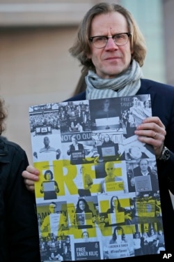 FILE - Human rights activists stage a protest outside a court in Istanbul, Jan. 31, 2018 where eleven human rights activists, accused of belonging to and aiding terror groups, stood trial.