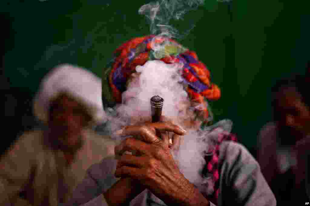 An Indian villager smokes tobacco as he joins other economically backward protesters during a rally demanding pension for elderly poor citizens in New Delhi.