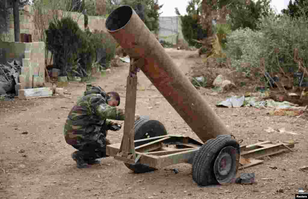 A Syrian Army soldier loyal to Syrian President Bashar al-Assad inspects a mortar used by Free Syrian Army fighters, in Ard al-Hamra, Aleppo, Feb. 27, 2014.