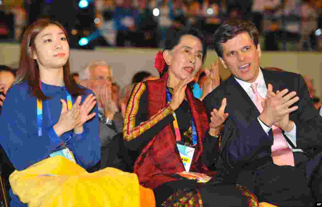 Aung San Suu Kyi flanked by Olympic figure skating gold medalist Kim Yu-na of South Korea, and Timothy Perry Shriver, chairman and CEO of the Special Olympics, applauds at the opening of the Special Olympics World Winter Games in Pyeongchang, South Korea,
