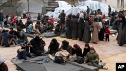 FILE - Displaced Syrian families take refuge in a school that has been turned into a temporary shelter in the Qudsaya neighborhood on the outskirts of Damascus, Syria, Feb. 23, 2015. Monitors say hundreds of civilians fled villages in the Barada Valley outside the Syrian capital Sunday, fleeing airstrikes by government forces and their Russian allies.