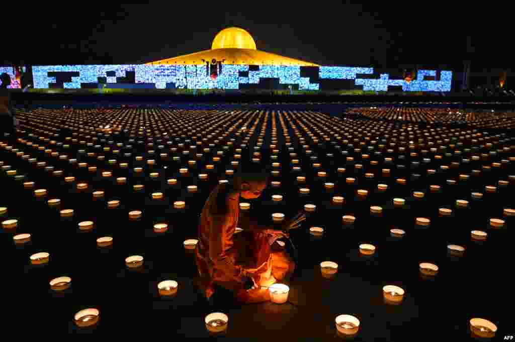 A Buddhist monk lights candles to commemorate Visakha Bucha Day or Vesak Day, a celebration of the birth, enlightenment and death of the Lord Buddha, held on the full moon of the third lunar month in the Buddhist calendar, at Wat Dhammakaya Buddhist temple in Bangkok, Thailand.