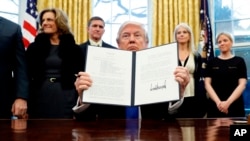 El Presidente Donald Trump sostiene un Memorando Presidencial firmado en la Oficina Oval, este sábado 28 de enero en Washington. El documento ordena a su administración "desarrollar un plan integral para derrotar a ISIS". 
