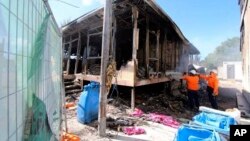 This photo supplied by Australian Department of Immigration and Citizenship shows workers extinguishing the last smouldering embers after some125 asylum seekers rioted in Nauru, Friday July 19, 2013. 