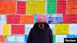 A woman looks at job advertisements on a wall in Qingdao West Coast New Zone in Shandong province, China, Jan. 17, 2019.