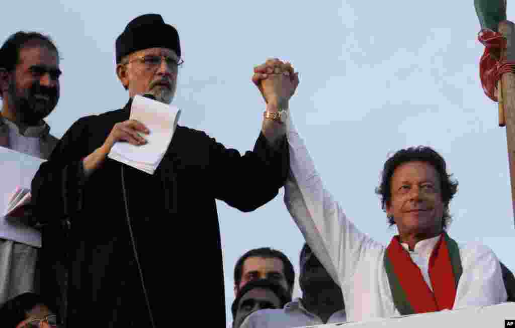 Pakistan&#39;s fiery cleric Tahir-ul-Qadri (second left) and cricketer-turned-politician Imran Khan (right), jointly raise their hands for their supporters during a protest near the prime minister&#39;s home in Islamabad, Sept. 2, 2014.