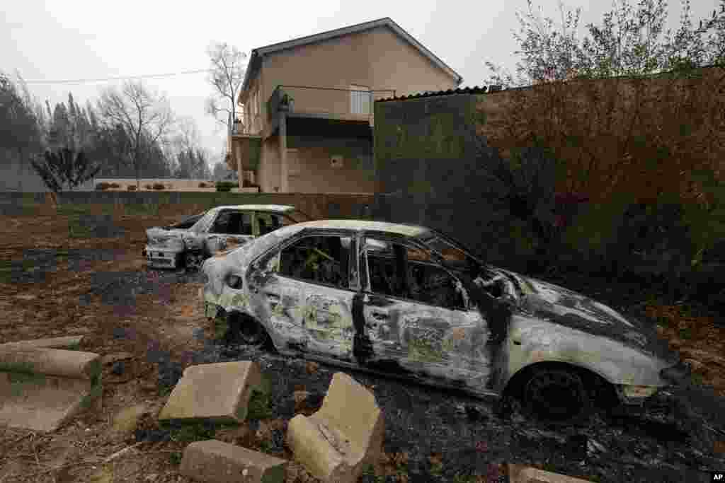 Burned cars are seen next to a house near Penacova, northern Portugal. Wildfires killed at least 27 people, injured dozens more and left an unconfirmed number of missing in the country&#39;s second such tragedy in four months, officials said.