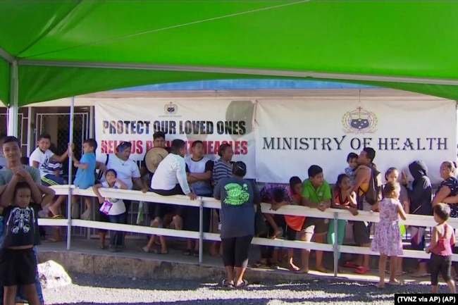 In this November 2019, image from video, children with parents wait in line to get vaccinated outside a health clinic in Apia, Samoa.