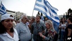 Protesters holding national flags take part in an anti-austerity rally in front of the parliament in Athens, Greece, June 17, 2015.