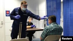 U.S. Coast Guard Health Technician Nathan Wallenmeyer (L) and Customs Border Protection (CBP) Supervisor Sam Ko conduct pre-screening measures on a passenger arriving from Sierra Leone at O'Hare International Airport's Terminal 5 in Chicago, Illinois, Oct. 16, 2014.