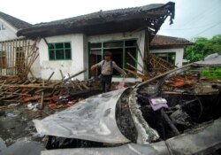 Seorang petugas polisi memeriksa kerusakan rumah anggota Ahmadiyah setelah diserang di Pandeglang, Banten, Senin, 7 Februari 2011. (Foto: AP)