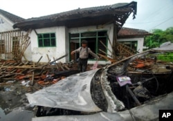 Seorang petugas polisi memeriksa kerusakan rumah anggota Ahmadiyah setelah diserang di Pandeglang, Banten, Senin, 7 Februari 2011, sebagai ilustrasi. (Foto: AP)