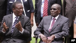Emmerson Mnangagwa, left, Vice President of Zimbabwe chats with Zimbabwean President Robert Mugabe after the swearing in ceremony at State House in Harare, Dec, 12, 2014. 