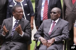 Former Vice President Emmerson Mnangagwa, left, chats with Zimbabwean President Robert Mugabe after the swearing in ceremony at State House in Harare, Dec, 12, 2014.