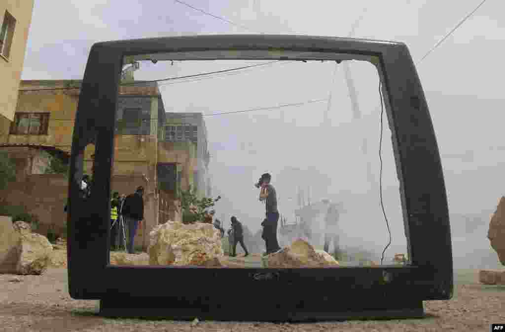Sebuah gambar yang diambil dari bingkai yang tersisa dari televisi yang hancur memperlihatkan para demonstran Palestina dalam bentrokan dengan pasukan Israel di desa&nbsp;​Kfar Qaddum, dekat Nablus di Tepi Barat.