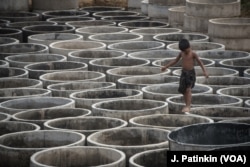 A Rohingya refugee child walks among concrete rings to be used for drainage in preparation for the annual rainy season in Bangladesh refugee camps.