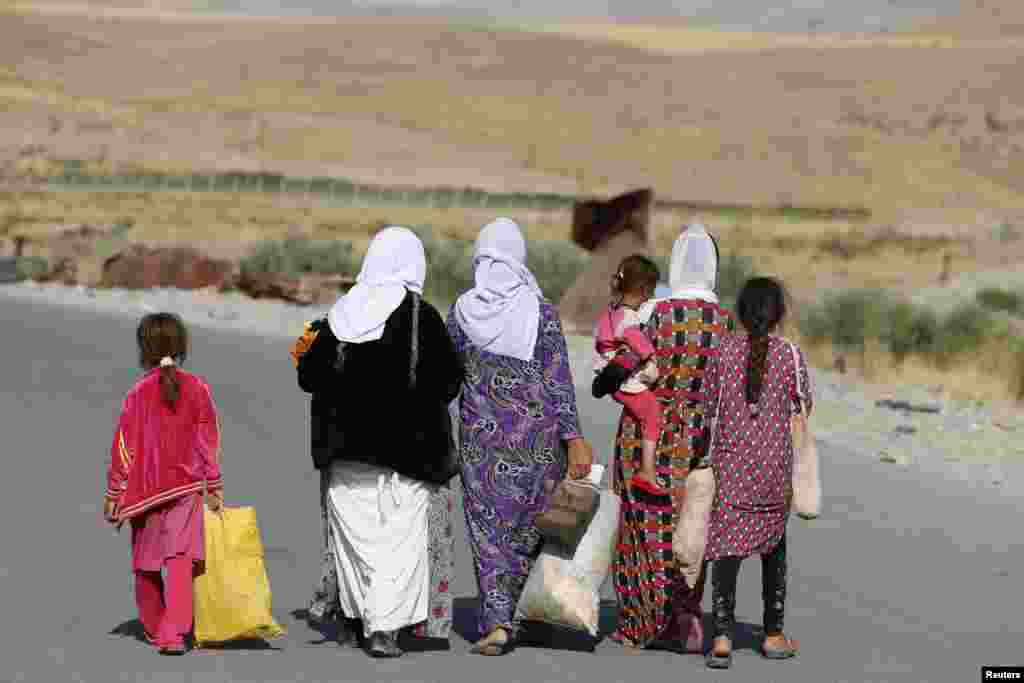 Perempuan dan anak-anak dari kelompok minoritas sekte Yazidi mengungsi dari kekerasan di kota Sinjar di Irak, berjalan menuju kamp pengungsi di Fishkhabour, provinsi Dohuk (14/8). (Reuters/Youssef Boudlal)