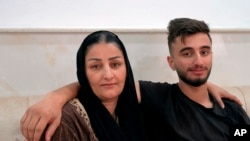 Sarkawt Selim, 19, who returned recently from Minsk after failing to cross the border into Poland, sits with his mother Adla, in their house in Dahuk, Iraq, Nov. 19, 2021.