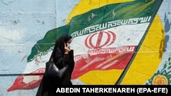 An Iranian woman walks next to a wall painting in a street of Tehran, Iran, 22 June 2019. 
