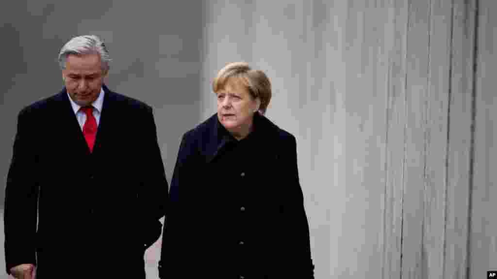 La chancelière allemande Angela Merkel, à droite, et le maire de la capitale allemande Berlin, Klaus Wowereit marchent le long de ce qui reste du mur de Berlin sur le site mémorial du mur de Berlin à Bernauer Strasse, Berlin, Allemagne. 