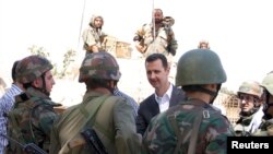 Syria's President Bashar al-Assad, center, chats with military personnel during visit to military site in Daraya,Aug. 1, 2013, SANA handout photo.
