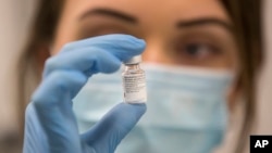 A worker holds a bottle of the Pfizer-BioNTech COVID-19 vaccine, as the mass public vaccination program gets underway at Southmead Hospital in Bristol, England, Tuesday Dec. 8, 2020. (Graeme Robertson/Pool via AP)