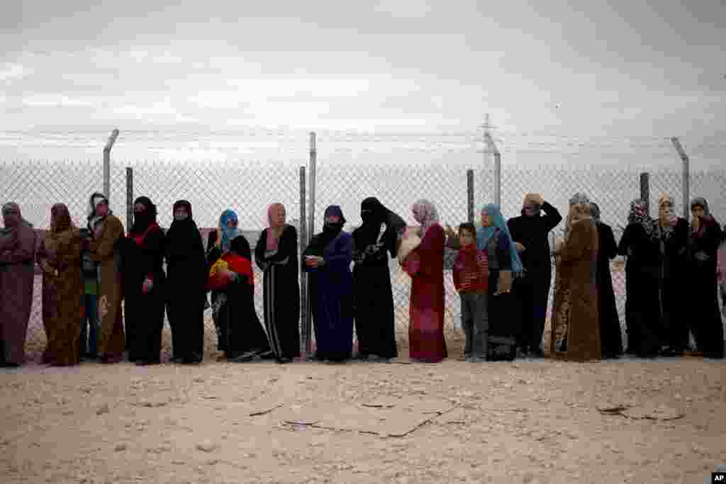 Syrian refugee women stand in line to receive winter aid kits at Zaatari refugee camp, near the Syrian border, in Mafraq, Jordan, Dec. 3, 2013. 