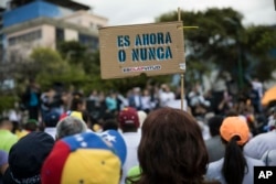 A member of the opposition holds a sign with message that reads in Spanish:"It's now or never", during a rally to propose amnesty laws for police and military, in Las Mercedes neighborhood of Caracas, Venezuela, Jan. 29, 2019.