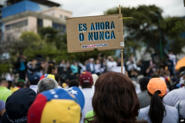 A member of the opposition holds a sign with message that reads in Spanish:"It's now or never", during a rally to propose amnesty laws for police and military, in Las Mercedes neighborhood of Caracas, Venezuela, Jan. 29, 2019.