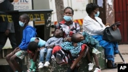 A mother takes time to rest with her children in Harare, Zimbabwe, Nov, 26, 2021. A slew of nations have moved to stop air travel from southern Africa, and stocks have plunged in Asia and Europe in reaction to news of a new, potentially more transmissible COVID-19 variant. 