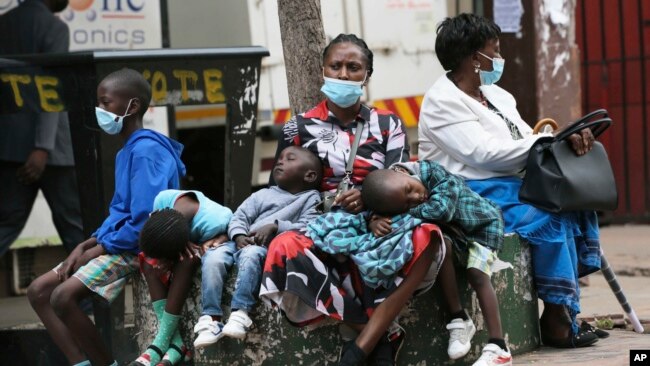 A mother takes time to rest with her children in Harare, Zimbabwe, Nov, 26, 2021. A slew of nations have moved to stop air travel from southern Africa, and stocks have plunged in Asia and Europe in reaction to news of a new, potentially more transmissible COVID-19 variant.