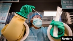 北京一名医护人员正在给居民进行新冠病毒核酸检测。（2021年10月20日）